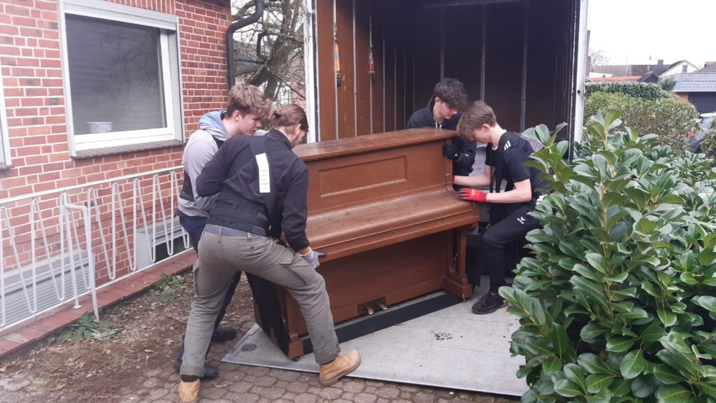 Mitarbeiter von Klaviertransport Lüneburg verladen ein Klavier in einen LKW