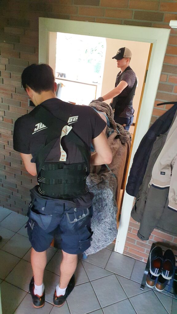 Mitarbeiter von Klaviertransport Lüneburg tragen ein Klavier durch eine Tür